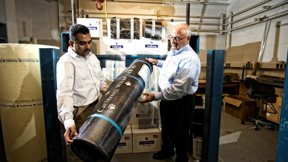 Abheetha Peiris (left) and Issam Harik (right) holding a roll of CatStrong carbon-fiber panels